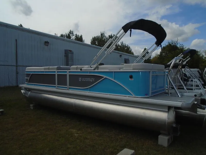Slide: The Image of 2025 Godfrey Sweetwater 2286 C pontoon boat with blue accents, parked outdoors. - 19