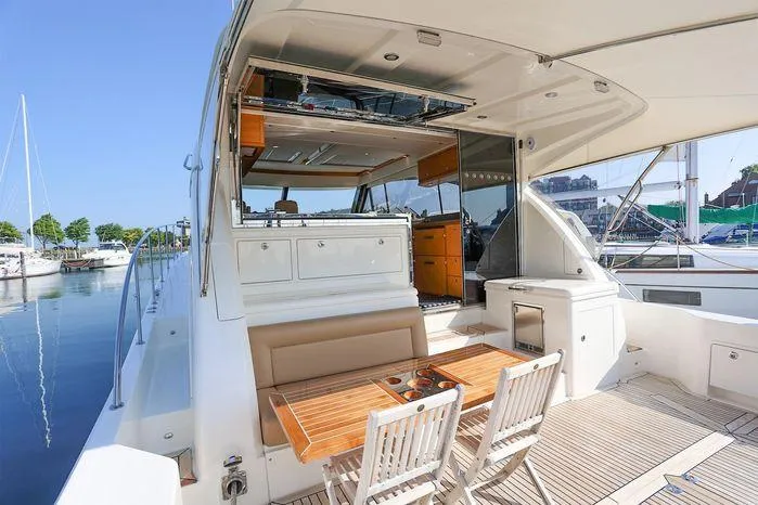 Slide: The Image of 2016 Riviera 525 SUV yacht with outdoor dining area and marina view. - 2