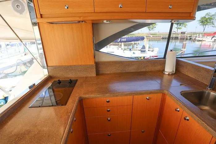 Slide: The Image of 2016 Riviera 525 SUV kitchen with wooden cabinets and marina view. - 24