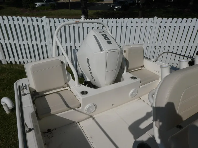Slide: The Image of 2025 Boston Whaler 210 Montauk boat with Mercury outboard motor, white interior, and fenced yard. - 10