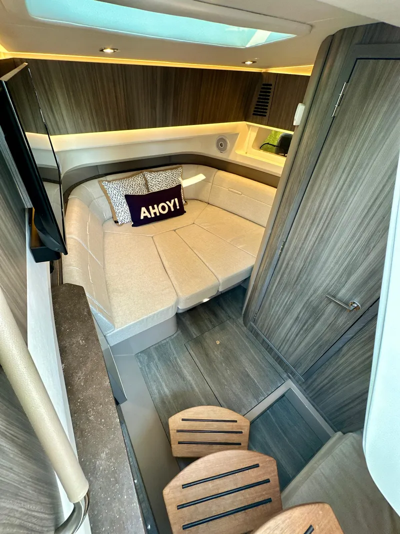 Slide: The Image of 2021 Sea Ray SLX 400 Outboard cabin interior with cozy bed and "Ahoy!" pillow. - 15