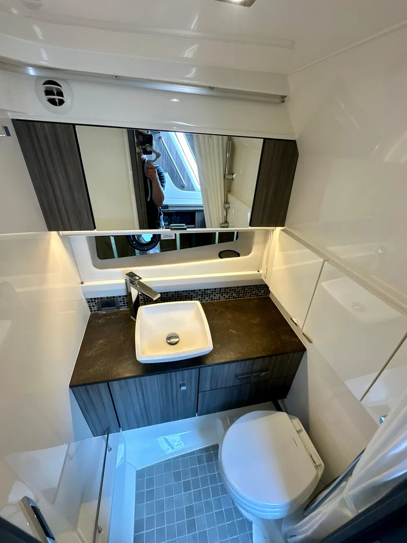 Slide: The Image of 2021 Sea Ray SLX 400 Outboard bathroom with modern sink, mirror, and toilet. - 20