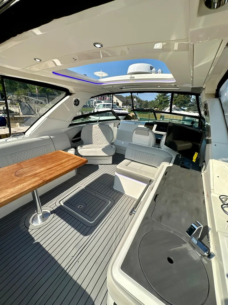 Slide: The Image of 2021 Sea Ray SLX 400 Outboard interior with seating, table, and helm in sunlight. - 26