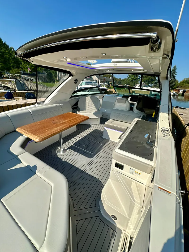 Slide: The Image of 2021 Sea Ray SLX 400 Outboard boat interior with seating and table, docked outdoors. - 3