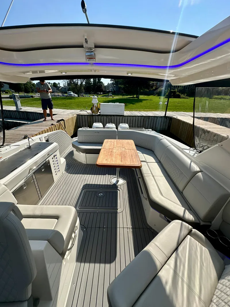 Slide: The Image of 2021 Sea Ray SLX 400 Outboard interior with spacious seating and wooden table, docked outdoors. - 6