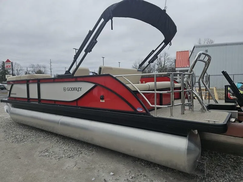 Slide: The Image of 2025 Godfrey Sweetwater 2286 SFL pontoon boat with canopy and seating, parked outdoors. - 7