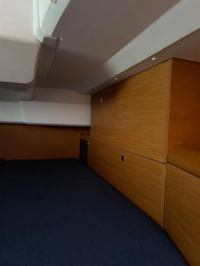 Slide: The Image of Interior cabin of 2016 Jeanneau Sun Odyssey 479 sailboat, featuring wood paneling and blue carpet. - 28