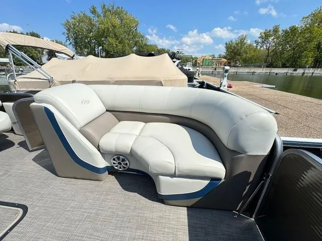 Slide: The Image of 2021 Manitou RF 23 Oasis VP boat with luxurious seating, docked by a serene waterfront. - 8