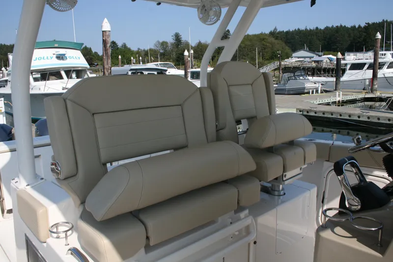 Slide: The Image of 2018 Pursuit S 328 Sport boat seats at marina, featuring beige upholstery and modern design. - 12