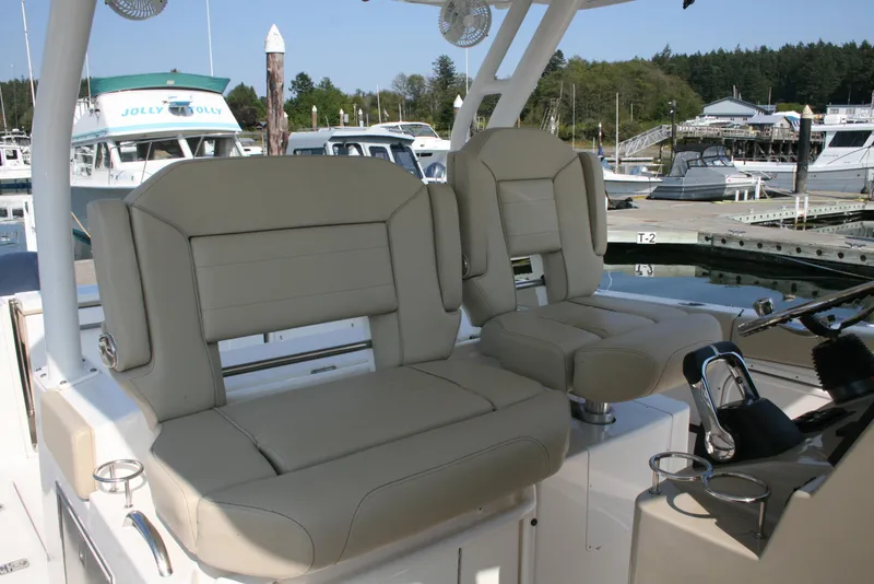 Slide: The Image of 2018 Pursuit S 328 Sport boat seats at marina, featuring beige upholstery and modern design. - 13