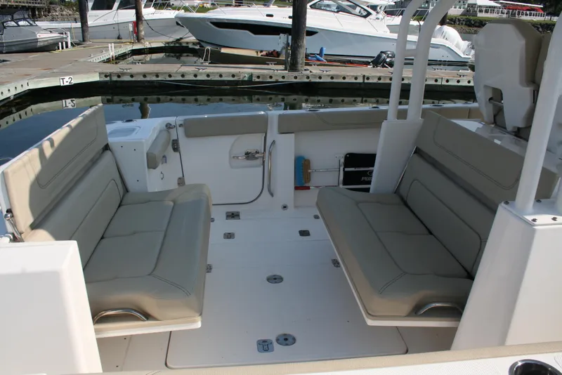 Slide: The Image of 2018 Pursuit S 328 Sport boat interior with beige seating at a marina. - 8