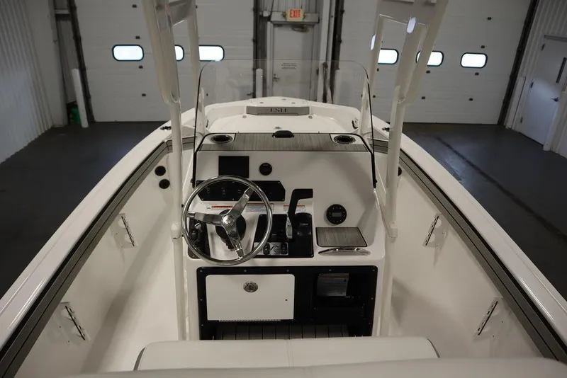 Slide: The Image of 2025 Yamaha Boats 190 FSH Sport interior, featuring steering console and controls in a garage setting. - 23