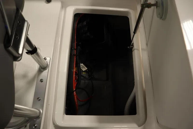 Slide: The Image of 2025 Yamaha Boats 190 FSH Sport storage compartment with visible wiring and hydraulic support. - 34