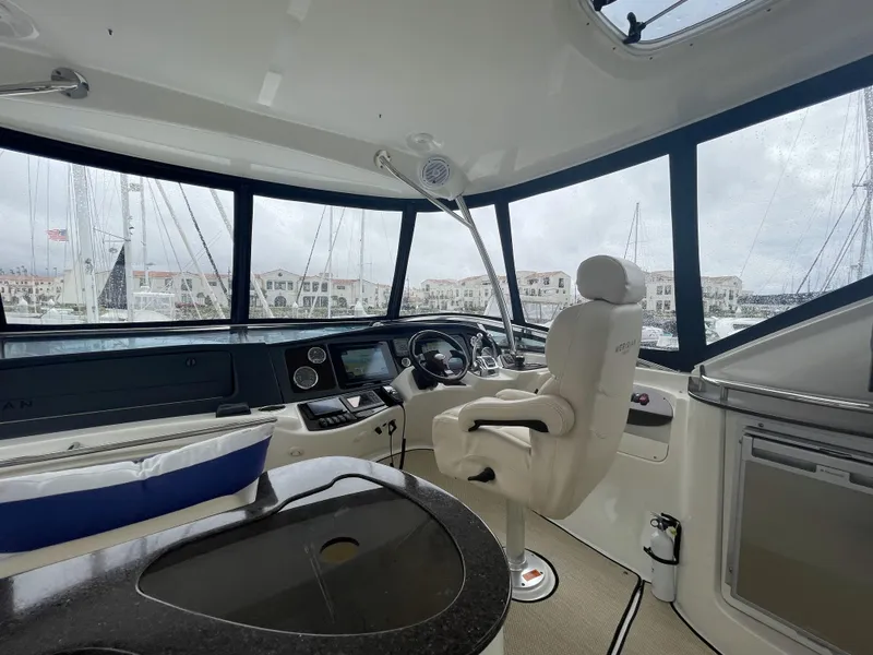 Slide: The Image of Interior of 2011 Meridian 441 Sedan Bridge yacht, featuring helm and marina view. - 18