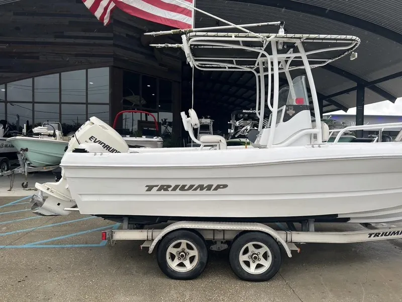 Slide: The Image of 2008 Triumph 215 CC boat on trailer, displayed outdoors with American flag. - 7