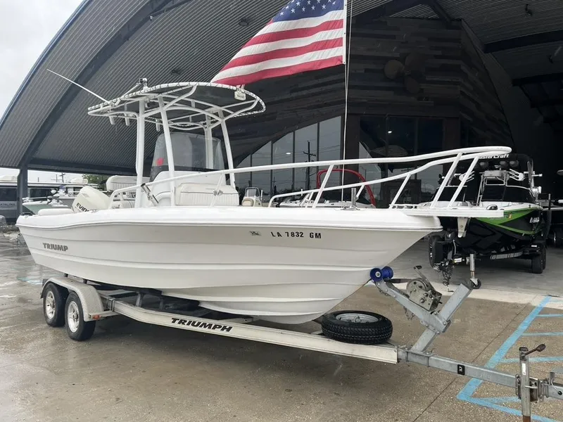 Slide: The Image of 2008 Triumph 215 CC boat on trailer with American flag in background. - 9