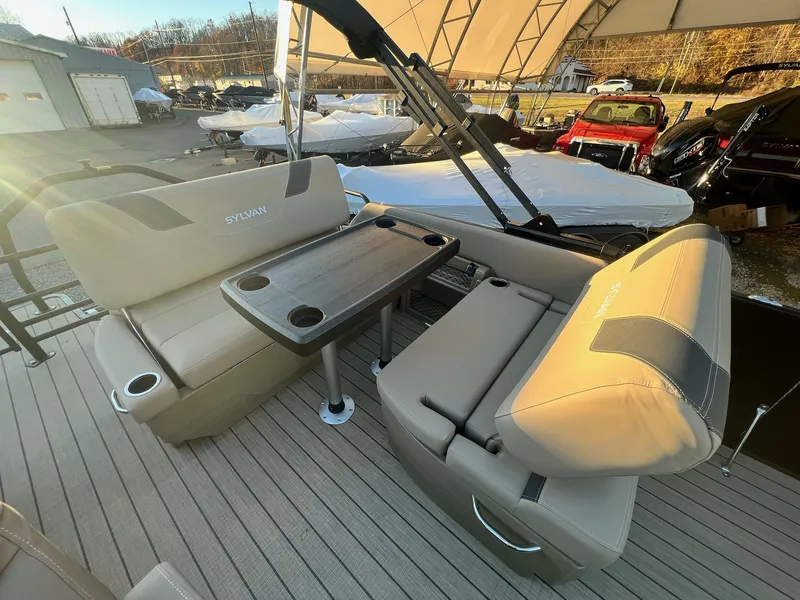 Slide: The Image of 2025 Sylvan L1 DLZ boat interior with beige seating and table, outdoor setting. - 23
