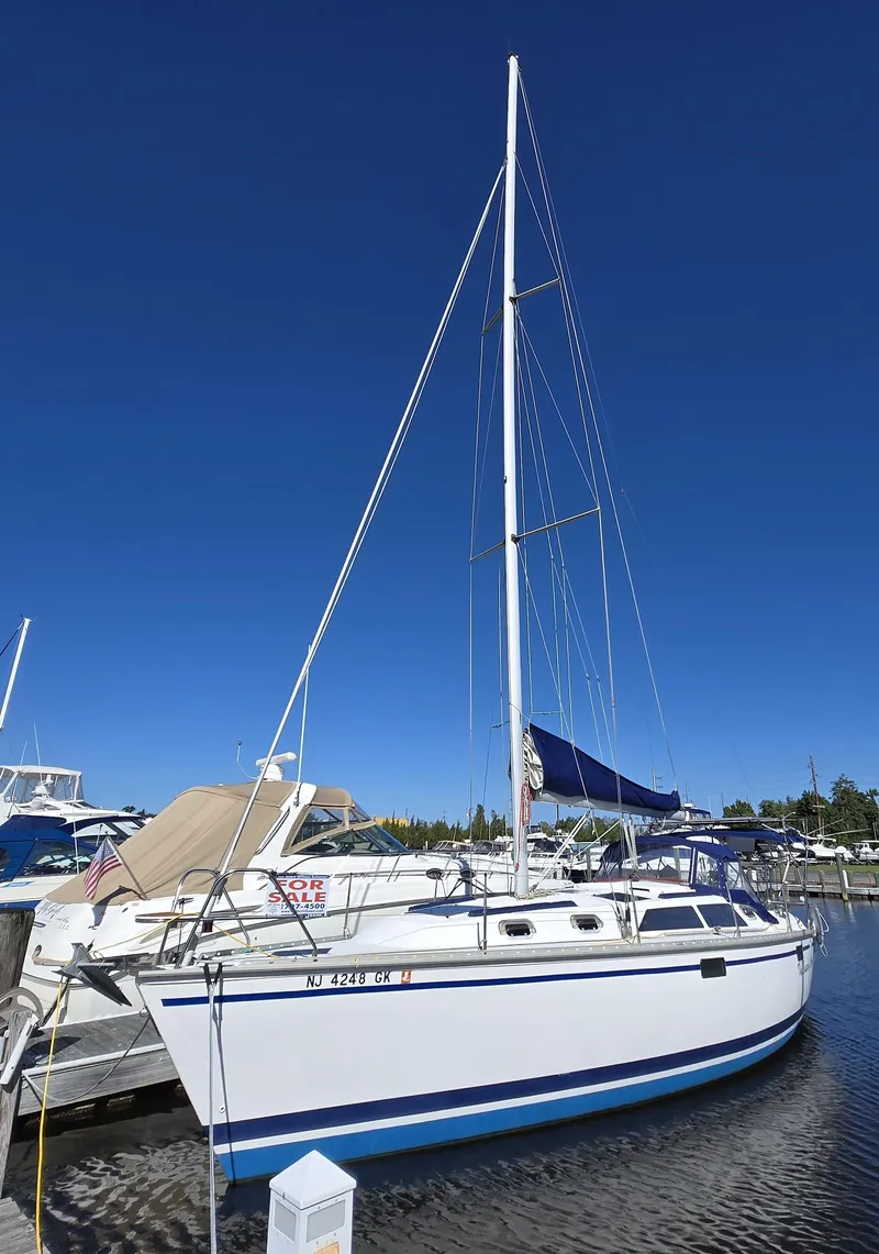 The Image of 1994 Hunter 33.5 sailboat docked at marina under clear blue sky. - 0