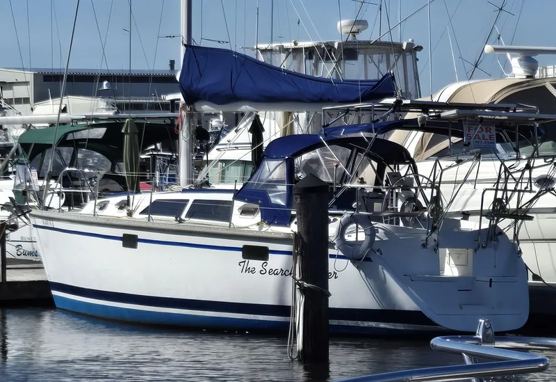 Slide: The Image of 1994 Hunter 33.5 sailboat docked in marina, featuring blue accents and covered sails. - 2