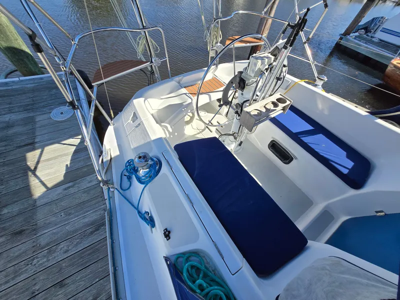 Slide: The Image of 1994 Hunter 33.5 sailboat cockpit with blue cushions and steering wheel, docked by the water. - 26