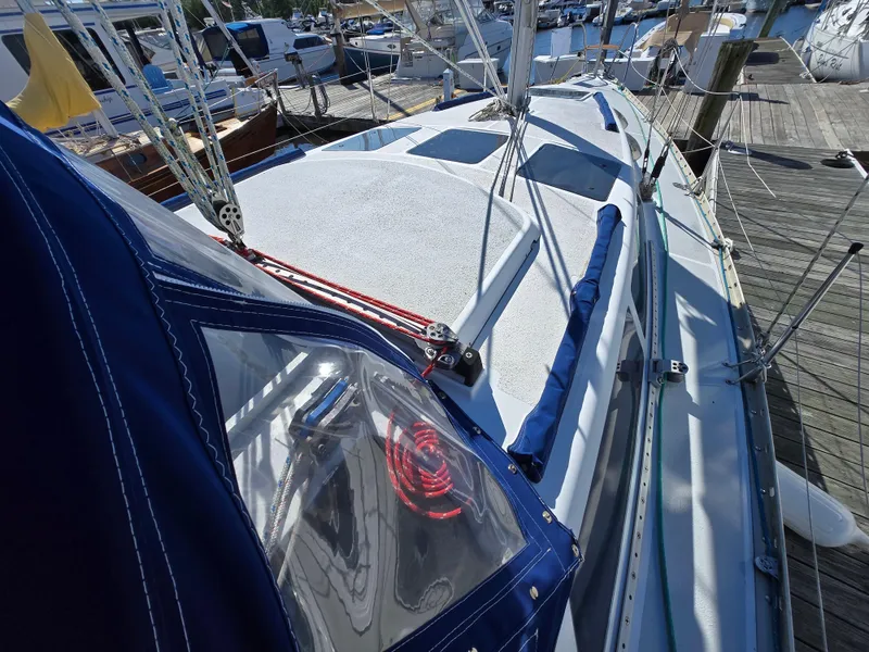 Slide: The Image of 1994 Hunter 33.5 sailboat docked, featuring blue canopy and deck details. - 28