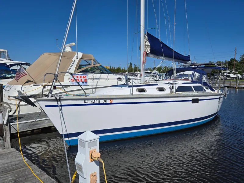 Slide: The Image of 1994 Hunter 33.5 sailboat docked, white hull, blue trim, "For Sale" sign visible. - 33