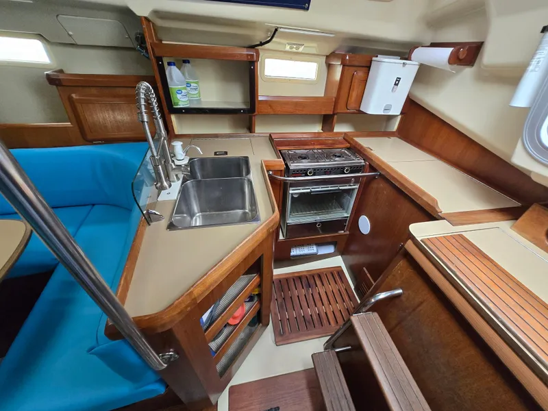 Slide: The Image of 1994 Hunter 33.5 yacht interior with kitchen, sink, stove, and blue seating. - 4