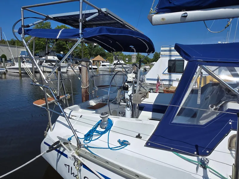 Slide: The Image of 1994 Hunter 33.5 sailboat docked at marina, featuring blue canopy and rigging. - 49