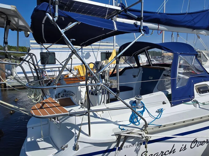 Slide: The Image of 1994 Hunter 33.5 sailboat docked, featuring blue canopy and solar panels. - 6