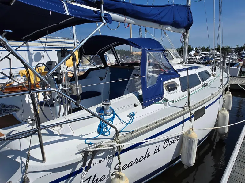 Slide: The Image of 1994 Hunter 33.5 sailboat docked at marina, featuring blue canopy and white hull. - 8