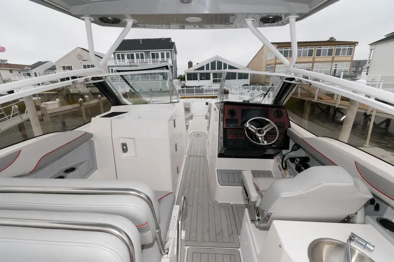 Slide: The Image of 2023 Solara S-250 DC boat interior with modern helm and seating, docked near waterfront homes. - 3
