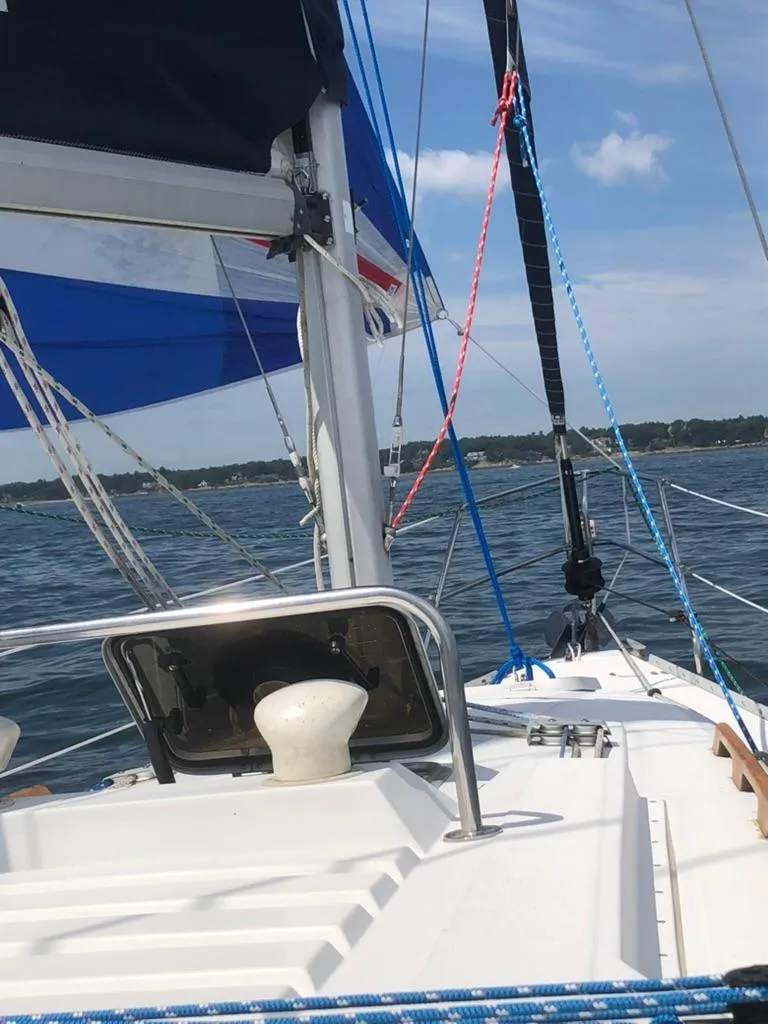 Slide: The Image of 1987 Hunter 31 sailboat on open water, featuring deck and rigging under clear skies. - 2