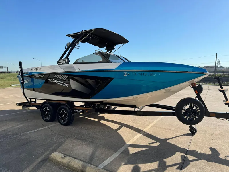 Slide: The Image of 2020 Tigé 23 RZX boat on trailer, blue and black design, parked in sunny lot. - 4