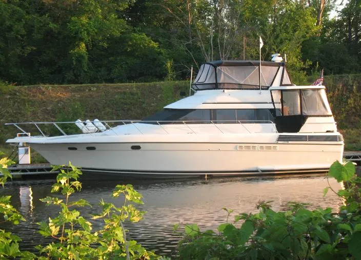 The Image of 1989 Silverton Aft Cabin 46 yacht docked on a serene waterway, surrounded by lush greenery. - 1