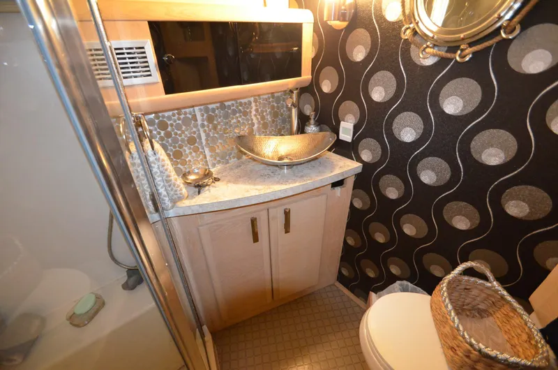 Slide: The Image of 1989 Silverton Aft Cabin 46 bathroom with modern sink, patterned wallpaper, and shower. - 23