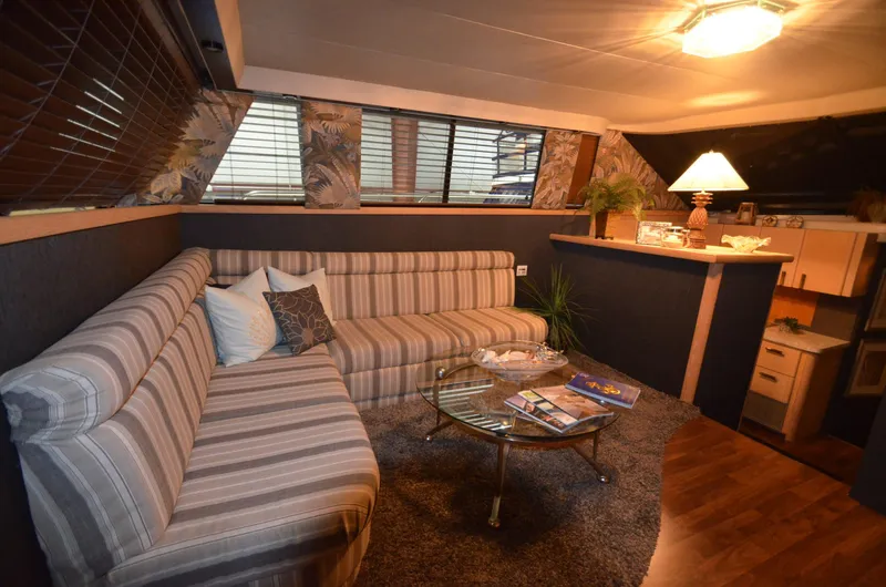 Slide: The Image of 1989 Silverton Aft Cabin 46 interior with striped sofa, glass table, and cozy lighting. - 3