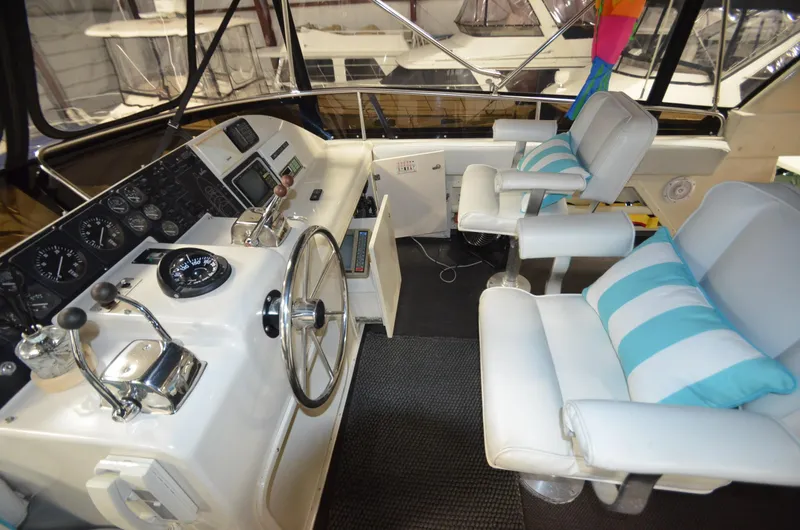 Slide: The Image of 1989 Silverton Aft Cabin 46 yacht helm with white seating and striped cushions. - 30