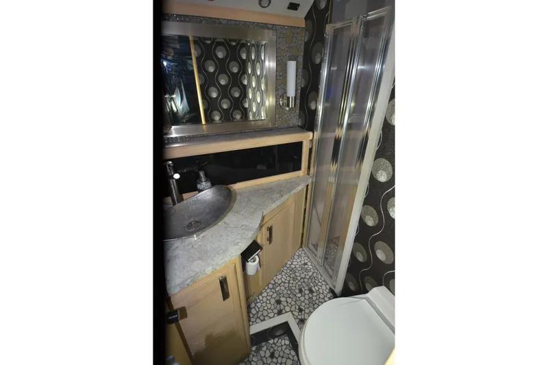 Slide: The Image of 1989 Silverton 46 Aft Cabin bathroom with modern sink, shower, and patterned wallpaper. - 46