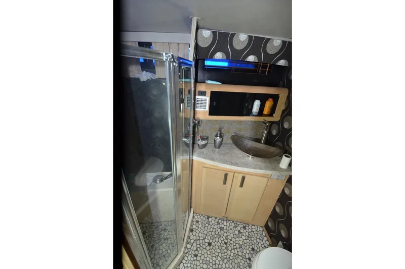 Slide: The Image of 1989 Silverton 46 Aft Cabin bathroom with modern sink, shower, and patterned wallpaper. - 48