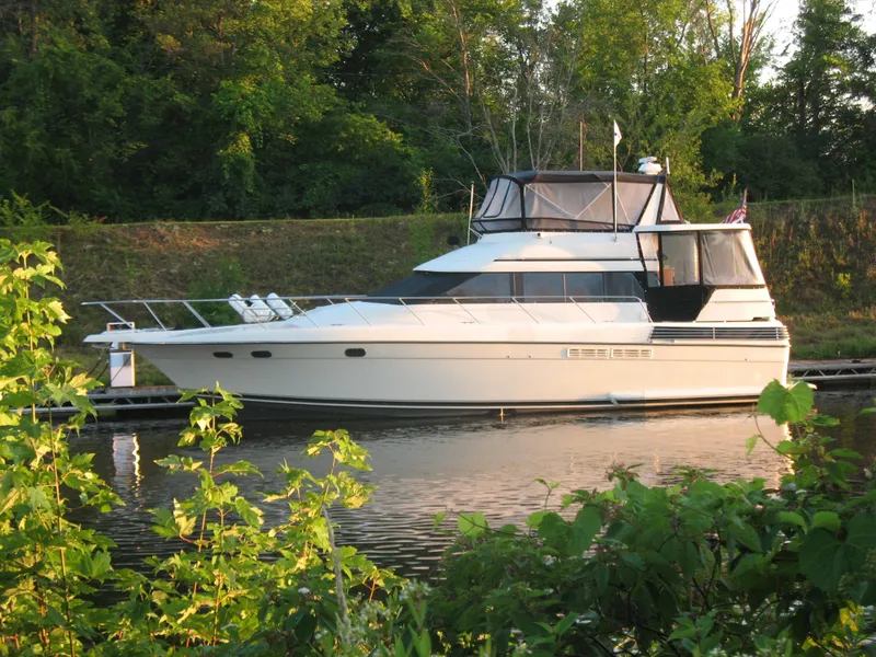 Slide: The Image of 1989 Silverton Aft Cabin 46 yacht docked by lush greenery. - 60
