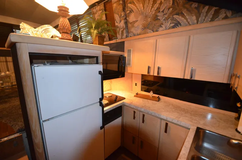 Slide: The Image of 1989 Silverton Aft Cabin 46 yacht kitchen with white cabinets, countertop, and appliances. - 7