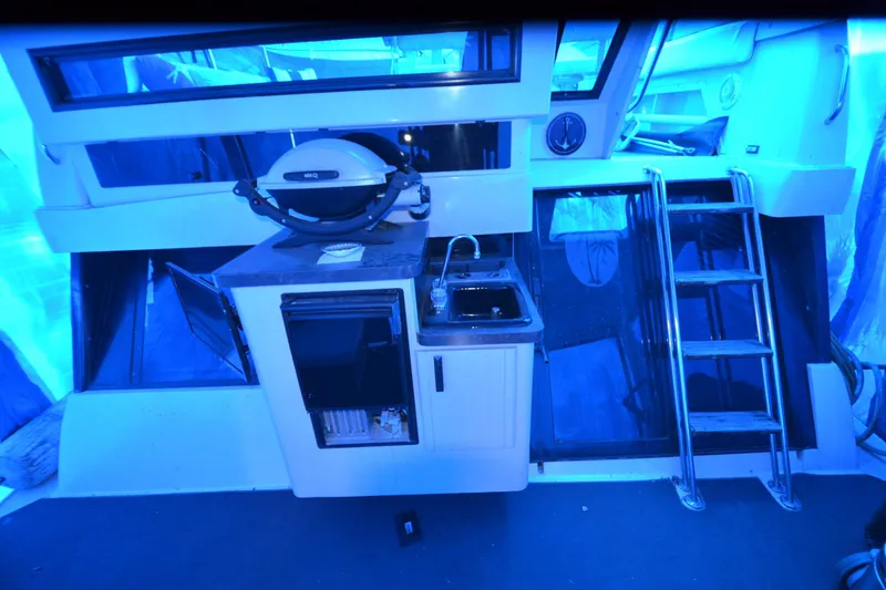 Slide: The Image of 1989 Silverton 46 Aft Cabin interior with kitchenette, sink, and ladder under blue lighting. - 71