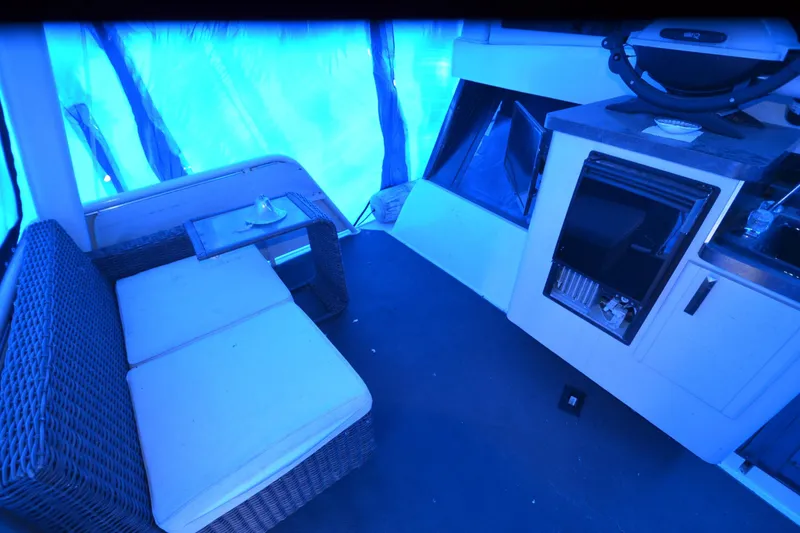 Slide: The Image of 1989 Silverton 46 Aft Cabin interior with wicker seating and kitchenette under blue lighting. - 74