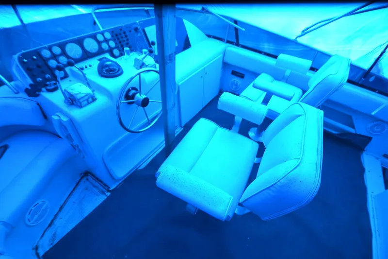 Slide: The Image of 1989 Silverton 46 Aft Cabin helm with steering wheel and control panel under blue cover. - 76