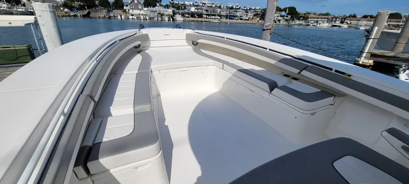 Slide: The Image of 2023 Regulator 34 boat interior with spacious seating, docked by a scenic waterfront. - 17