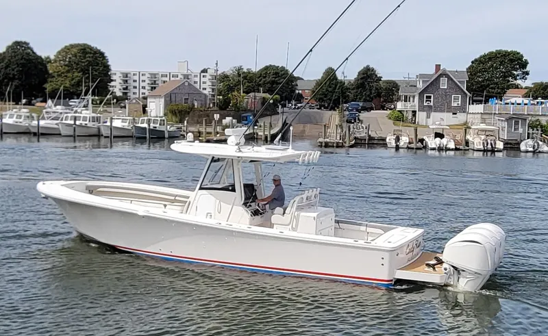 Slide: The Image of 2023 Regulator 34 boat cruising in a marina with coastal buildings in the background. - 2