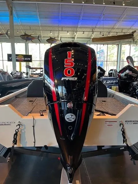 Slide: The Image of 2025 Tracker Pro Team 195 Tournament Edition boat with powerful 150 HP engine in showroom. - 2