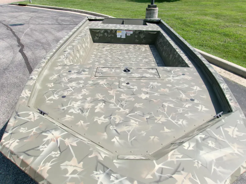 Slide: The Image of 2025 Tracker Grizzly 1754 Jon boat with camouflage design on pavement. - 2