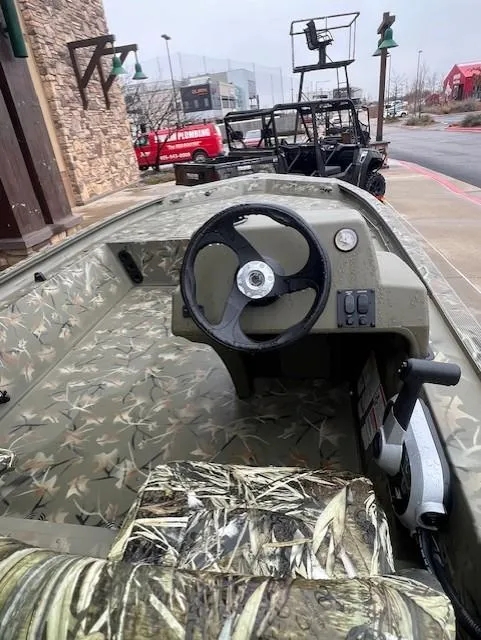 Slide: The Image of 2025 Tracker Grizzly 1754 SC boat with camouflage interior, parked outdoors. - 3