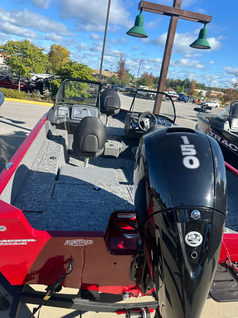 Slide: The Image of 2025 Tracker Pro Guide V-175 Combo boat with 150 HP engine in a parking lot. - 2